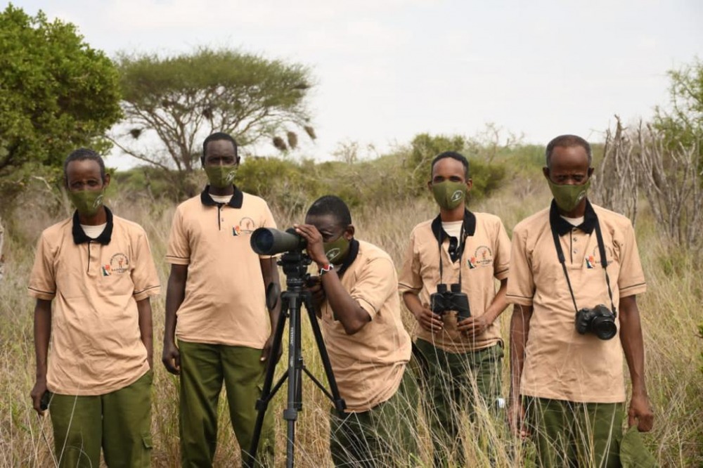 5 Hirola staff members, standing while the center person takes a photograph