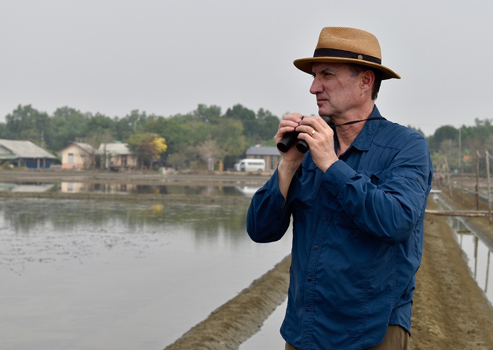 Mark looks for bird species while visiting a project site.