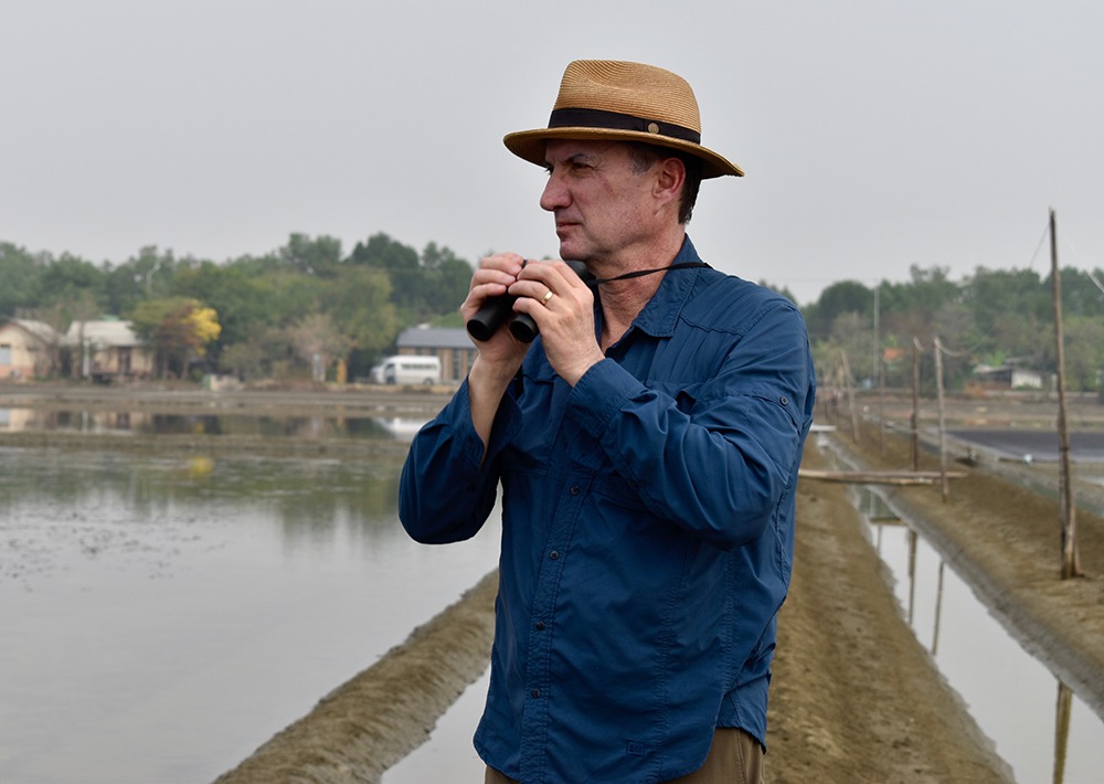 Mark looks for bird species while visiting a project site.